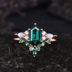 an emerald and white diamond ring on top of a rock with diamonds in the middle