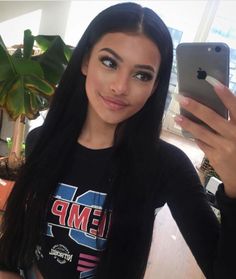 a woman with long black hair holding an iphone