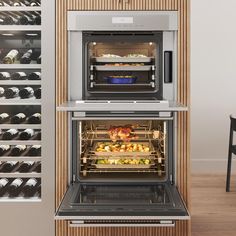 two ovens side by side with food cooking in them and wine bottles on the wall