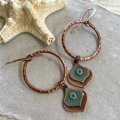 These bohemian hand painted copper hoop and drop earrings are a unique and striking accessory that have been crafted in our island studio using a special house patina paint blend resulting in a beautiful palette reminiscent of the colorful textile art found in many beach-side Mexican villages. Once the patina process is complete, we buff and seal the copper for durability and to prevent tarnishing. Each pair of these earrings are one-of-a-kind, with variations in the patina that add to their handmade charm. Color: Antique Copper with Blue Size: 2.5 Inches from Lobe Ear Wire: Choice of Antique Copper or Sterling Silver French Ear Hooks with Safety Back Lightweight and Comfortable Handmade in the USA Gift Ready: Your earrings come in a gift pouch ready for giving or to treasure for yourself. Bohemian Hand Painted Copper Earrings, Copper Dangle Jewelry With Patina, Unique Copper Earrings With Patina, Bohemian Copper Earrings With Patina, Unique Patina Copper Earrings, Patina Paint, Patina Copper, Beautiful Anklet, Colorful Textiles