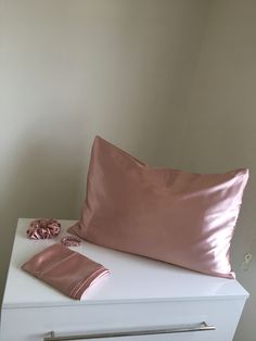 a pink pillow sitting on top of a white dresser next to a pair of scissors