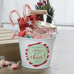 a bucket filled with candy canes and candies on top of a wooden table