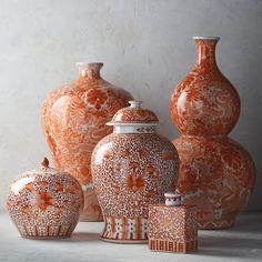 an assortment of orange vases and jars on a table