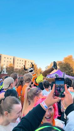 a group of people standing around each other taking pictures with their cell phones at an outdoor event