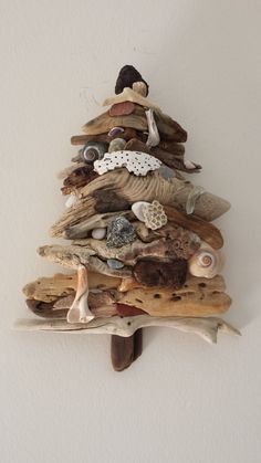 a small christmas tree made out of driftwood and seashells on a white wall