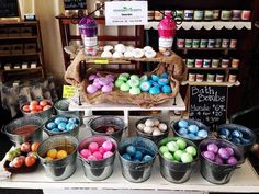 several buckets filled with colored eggs sitting on top of a table next to each other