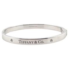 A Tiffany & Co. Diamond bangle, made of 18ct White Gold, and weighing 38.7 gm. Stamped: Tiffany & Co. AU 750. The bangle is set with 2 round, brilliant cut Diamonds, colour D-E and clarity VVS with a total weight of 0.10 ct. Metal: 18ct White Gold Carat: 0.10ct Colour: D-E Clarity: VVS Cut: Round Brilliant Weight: 38.7 grams Engravings/Markings: Signed Tiffany & Co. AU 750. Size/Measurement: Size Medium Current Condition: Excellent - Consistent with age and use. Accompanied by: This Tiffany & Co Luxury Polished Diamond Bangle Bracelet, Luxury Diamond Bangle With Polished Finish, Luxury Hallmarked Diamond Bangle Bracelet, Luxury Channel Set Bracelets For Anniversary, Classic Brilliant Cut Bangle For Gift, Classic Bangle With Brilliant Cut For Gift, Classic White Gold Cubic Zirconia Cuff Bracelet, Classic White Gold Diamond Cuff Bracelet, Classic White Gold Cuff Bracelet With Single Cut Diamonds