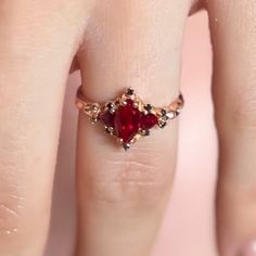 a close up of a person's hand with a ring on their finger and a red stone in the middle