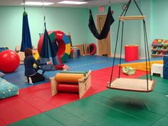 children's play area with swings, toys and other items on the floor in an indoor gym