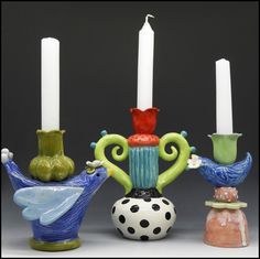 three candles sitting next to each other on top of vases with birds around them