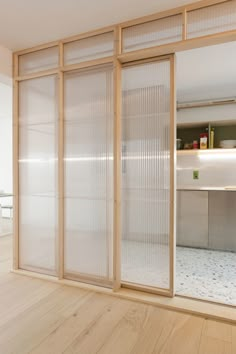 an empty room with wooden floors and sliding glass doors that lead into the kitchen area