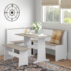 a kitchen table with two benches next to it and a rug in front of the window