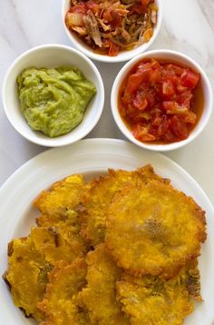 three plates with different types of food in them on a white table top next to bowls of guacamole, salsa and tortillas