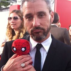 a man in a suit and tie holding a spider - man plush toy at an event