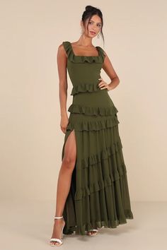 a woman wearing a green dress with ruffles on the side and thigh high heels