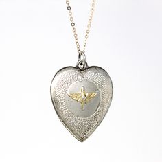 Historical vintage circa 1940s sterling silver Prop and Wings heart pendant! This classic pendant has a heart shape, and features the Prop and Wings Military emblem on the front, and is shown modeled on a brand new sterling silver 18" chain. A wonderful piece of vintage aviation sweetheart jewelry!  ERA - Circa 1940s - Retro METAL / MATERIAL - Sterling silver pendant, sterling silver chain MARKINGS / HISTORY - Back of pendant is marked "sterling"  CONDITION - Good vintage condition. Sterling silver metal has been professionally polished & cleaned. Age appropriate patina & wear remains. Amazing vintage military pendant!  SIZE / MEASUREMENTS - Chain Modeled: 18 inches, Pendant (including bail): 1 1/4 x 7/8 inches, Weight (without chain): 3.52 grams PRESENTATION - Listing includes a complimen Vintage Hallmarked White Gold Locket Necklace, Vintage Medallion Necklace With Polished Finish, Vintage White Gold Locket Necklace As A Gift, Vintage White Gold Locket Necklace Gift, Vintage White Gold Locket Necklace For Gift, Vintage Open Heart Engraved Locket Necklace, Vintage Engraved Open Heart Locket Necklace, Vintage Heart Charm Medallion Jewelry, Vintage Jewelry With Heart Charm Medallion