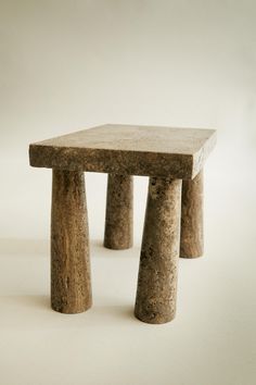 two stone stools sitting next to each other on a white surface in front of a wall