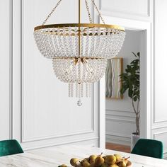 a chandelier hanging over a dining room table with fruit on the plate in front of it