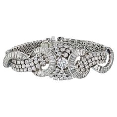 Crafted with unparalleled artistry and adorned with the most exquisite diamonds, our Art Deco Platinum Cluster Diamond 38.00cttw Bracelet is a testament to timeless elegance. Every aspect of this remarkable piece is a celebration of beauty and craftsmanship, designed to captivate the heart of your beloved. The bracelet boasts a stunning composition of round and baguette-shaped diamonds, meticulously arranged to form a breathtaking cluster on the wrist. At the center lies a magnificent 1.80ct rou Luxury Platinum Diamond Bracelet With Baguette Diamonds, Fine Jewelry Diamond Bracelets For Evening, Luxury Diamond Evening Bracelet, Evening Diamond Bracelet With Brilliant Cut, Luxury Evening Diamond Bracelet, Luxury Platinum Diamond Bracelet With Brilliant Cut, Luxury Platinum Diamond Bracelet With Accents, Luxury Platinum Diamond Bracelet With Diamond Accents, Evening Diamond Cut Diamond Bracelets