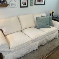 a white couch sitting on top of a wooden floor next to a wall with pictures above it