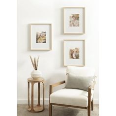 a white chair sitting next to a wooden table in front of three pictures on the wall