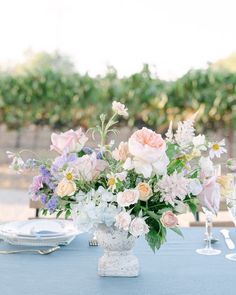 a vase filled with lots of flowers on top of a blue table cloth covered table