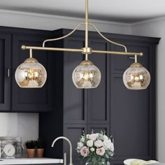 three lights hanging over a kitchen island in a home with black cabinets and white countertops