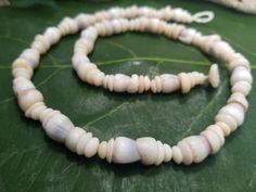 This is a very unique and vibrant piece made with Hawaiian white cone shells with puka shells collected from the beaches of Kauai, Hawaii. Puka shells are actually the tops of cone shells that have been tumbled in the ocean waves for many years. These leis are much more lightweight then a lei made with just puka shells. This necklace looks great on men and women. It is strung with 80lb' test braided nylon line, so it is very strong and can be worn in fresh or salt water. There are less Cone an P Handmade Spiritual Shell, Ocean-inspired Shell With Round Beads, Ocean-inspired Shell Beads, White Shell Necklace With Natural Stones, Adjustable Artisan Shell Necklace, Artisan White Shell Necklace For The Beach, Artisan Beaded Shell Necklace, Handmade Round Shell Beads, Handmade Shell Choker