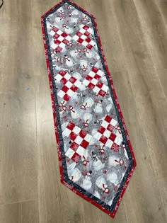 a red and white tie laying on top of a wooden floor next to a table