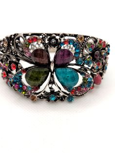 Elegant, hinged cuff bracelet encrusted with colorful array of sparking rhinestones. This bracelet measures approximately 8.5 inches in diameter and 2 inches wide in her front and .25 inches in the back.  I recommend measuring your wrist with a measuring tape or string that is 8.5 inches long to get an idea of the fit on your wrist. This bracelet is in very good condition.  This vintage treasure has been previously loved and worn and with any vintage item there might be slight imperfections, blemishes or inconsistencies.   Necklace arrives in a black velvet drawstring pouch. I would love to see you wearing your new necklace, please tag me on FB @Parididdles or on Instagram and if you're happy with your purchase please don't forget to write a review! Thank you for taking the time to visit m Metal Rhinestone Cuff Bangle Bracelet, Metal Bracelets With Multicolor Jeweled Details, Metal Rhinestone Cuff Bangle, Multicolor Crystal Bangle Bracelet, Multicolor Rhinestone Bangle Jewelry, Multicolor Rhinestone Bangle, Rhinestone Bangle Cuff Bracelet For Gift, Rhinestone Bangle Cuff Bracelet As Gift, Multicolor Metal Bracelets With Rhinestones