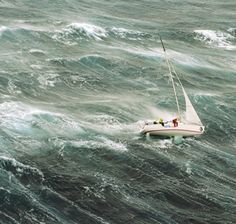 a sailboat in rough water with people on it