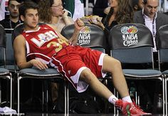 a basketball player is sitting in the middle of a game while eating pizza and drinking water