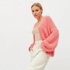 a woman in white jeans and a pink cardigan sweater is posing for the camera