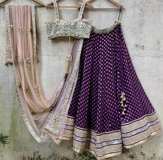 A three-piece aubergine lehenga set from the Priti Sahni collection. This beautiful raw silk butti purple lehenga with a heavy border of gota work detail is paired with a hand-embroidery bustier with mirror and pearl detail. This outfit is completed with a nude gota butti dupatta in net material. Zardosi Dupatta, Wine Lehenga, Mirror Lehenga, Hand Embroidered Dupatta, Work On Blouse, Pearl Border, Embroidered Bustier, Purple Lehenga, Mirror Work Lehenga