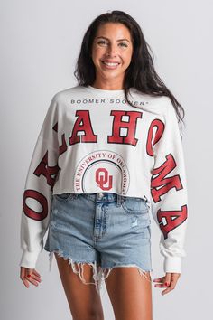 OU OKLA long sleeve crop sweatshirt from Lush Fashion Lounge women's boutique in Oklahoma City. Lush boutique in OKC has a variety of cute game day apparel and more! This trendy OU sweatshirt is a must have for game day! Officially licensed by the University of Oklahoma. Model is 5'7 size 27 wearing size small. 60% cotton 40% polyester White Cropped Sweatshirt For Streetwear, White Cropped Cotton Sweatshirt, White Cropped Cotton Sweater, White Long Sleeve Cropped Sporty Sweater, White Cotton Cropped Sweater, White Long Sleeve Crop Top With Graphic Print, Trendy Long Sleeve Tops For Game Day, White Cotton Cropped Sweater With Long Sleeves, White Long Sleeve Cotton Cropped Sweater