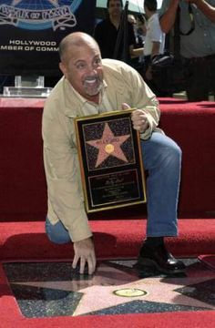 a man kneeling down next to a star on the hollywood walk of fame with his hand up