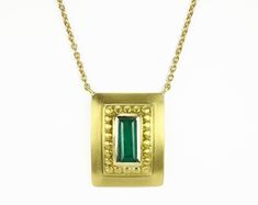 Displayed in a one of kind, green gold, Colombian emerald hand-made necklace. A divine 1.60-carat elongated emerald sits in a secure bezel setting. The alluring centerpiece displays a rich blue-green color, true to its prized origin; Muzo, Colombia. Beautiful clarity is seen in this gem as it is eye clean, small imperfections are natural, adding ambiance and character to the stone. A golden halo rises around the gemstone, providing texture and depth. A hand brushed satin finish is dexterously ap Formal Hallmarked Emerald Necklace, Yellow Gold Necklace With Emerald Rectangular Pendant, Gold Emerald Pendant Necklace With Bezel Setting, Rectangular Emerald Jewelry With Bezel Setting, Luxury Emerald Necklace With Bezel Setting, Emerald Gemstone Necklace For Celebration, Traditional Yellow Gold Emerald Necklace For Formal Occasions, Traditional Yellow Gold Emerald Necklace For Formal Events, Formal Emerald Rectangular Pendant Jewelry