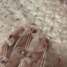 a close up of a person's hand on a bed with lace and pearls