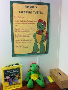 a stuffed turtle sitting on top of a wooden table next to a sign and books