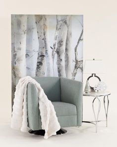 a chair with a blanket on it next to a table and wall mural in the background