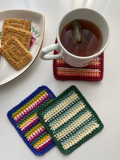 two coasters and a cup of tea on a table with crocheted placemats