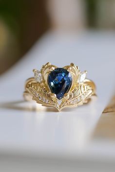 a heart shaped blue diamond ring sitting on top of a table next to other jewelry