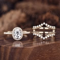 two wedding rings on top of a wooden table with other jewelry items in the background