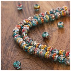 multicolored beaded necklace and earring set on wooden surface with beads scattered around