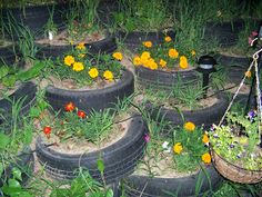 a bunch of tires that are sitting in the grass with flowers growing out of them