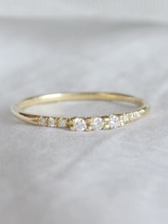 a yellow gold ring with five diamonds on it, sitting on a white cloth background