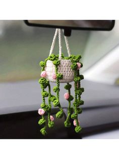 a crocheted decoration hanging from the dashboard of a car with pink and white flowers