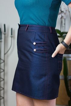 a woman wearing a skirt with buttons on the side and her hands behind her back