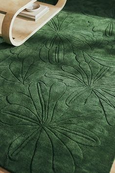 a green rug on the floor with a wooden chair in front of it and an object next to it