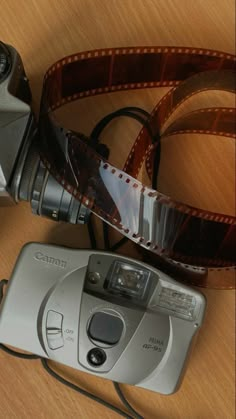 a camera and film on a table with a strap around it's body,